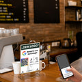 Trustyify Bewertungsaufsteller im Café mit Google QR-Code und NFC-Funktion – Gast hält Smartphone für Bewertung an den Aufsteller